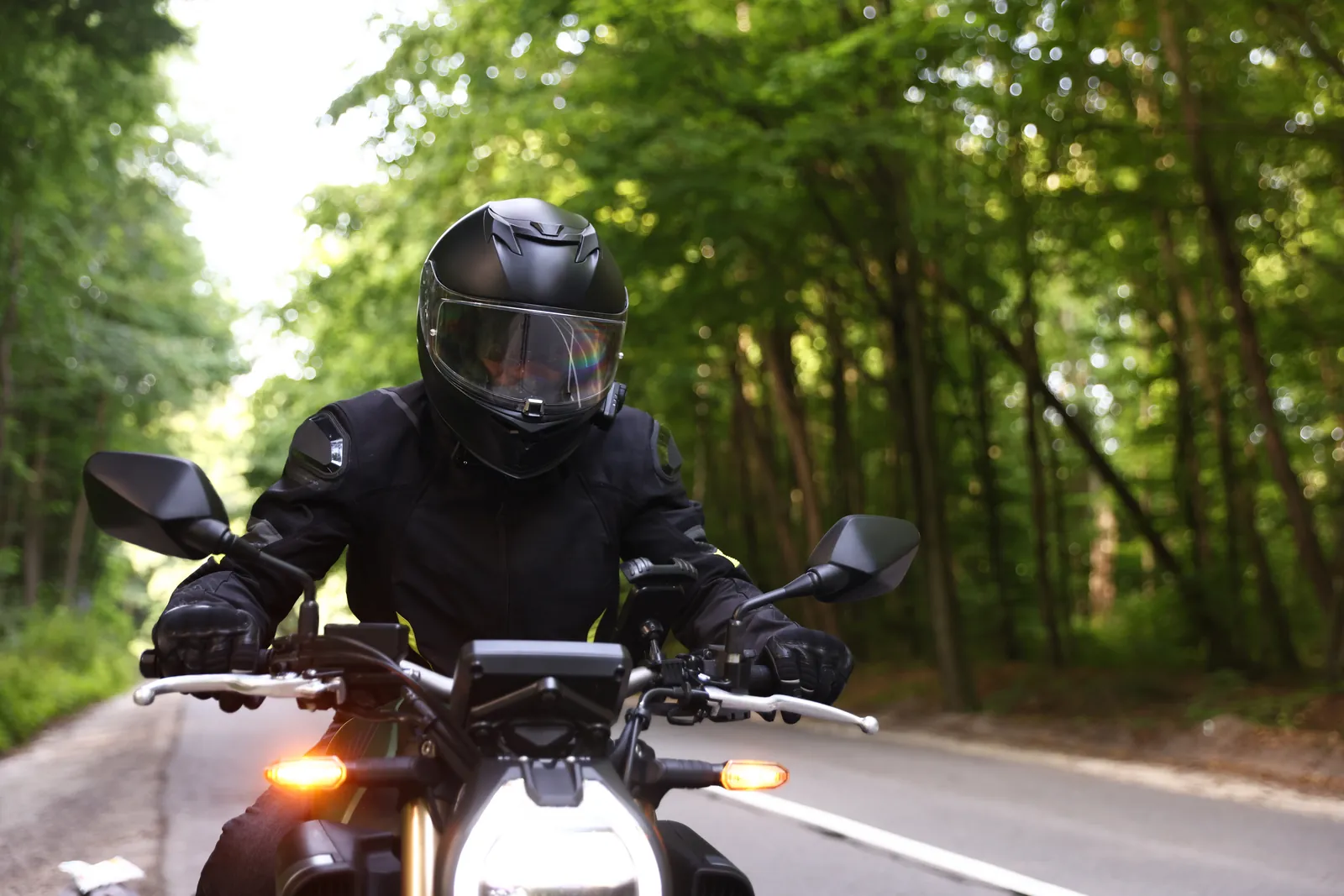 Motorradfahrer mit Integralhelm und Schutzkleidung auf einer Landstraße