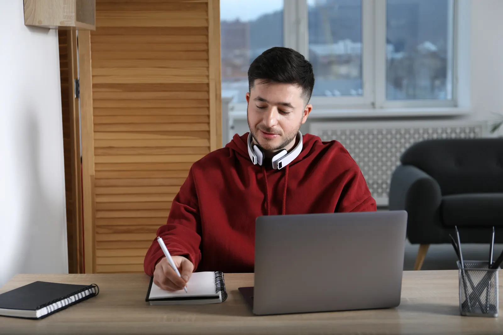 Junger Mann lernt am Laptop und schreibt die Prüfungsfragen mit